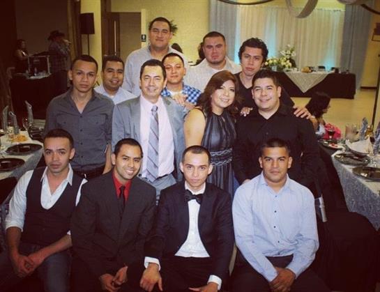 Friends gather and pose for a group picture at a formal event in a well-decorated hall.
