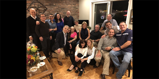 Friends gather together, smiling and posing for a group picture in a welcoming living room.