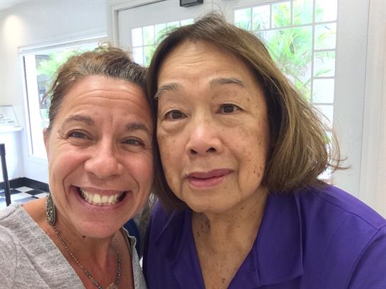 Two women smile widely, enjoying their time together at a senior care center setting.