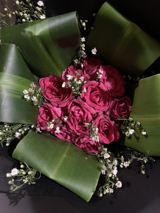 Bright red roses are beautifully arranged with lush green leaves, perfect for a celebration.