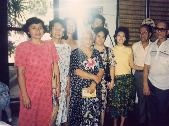 A diverse group of friends and family members gather together, smiling and celebrating indoors.