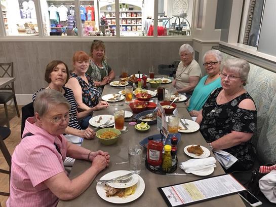 Friends gather at a table with food and drinks, sharing laughter and conversation.