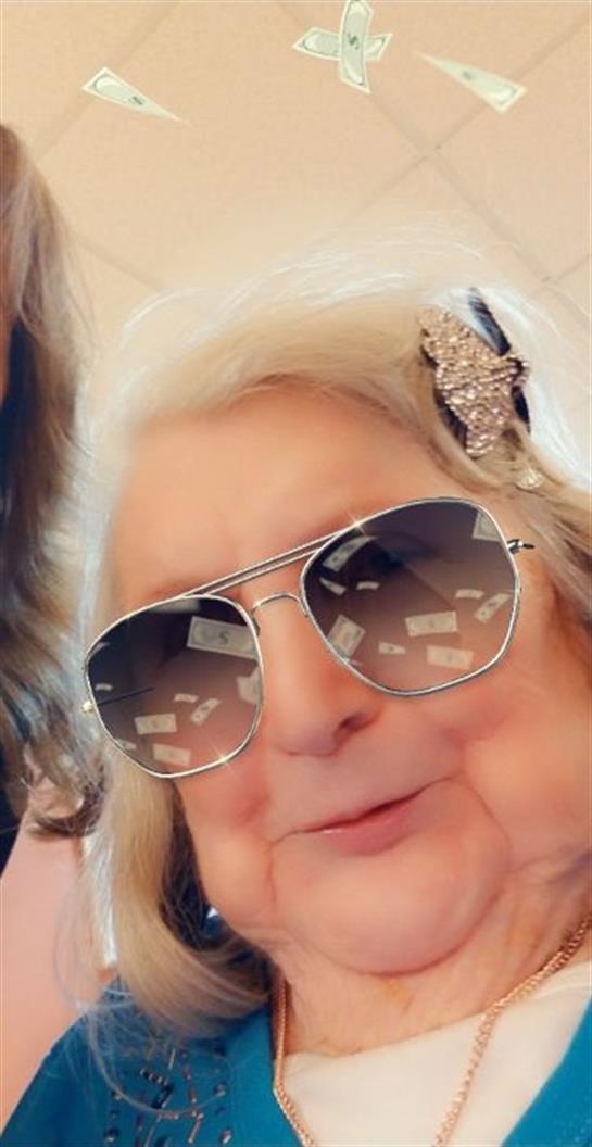 Outdoor gathering with an elderly woman wearing sunglasses and smiling, radiating joy and warmth.