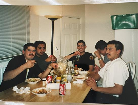 A group of friends sits around a table, sharing food and drinks in a relaxed setting.