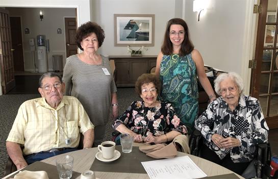 Five elderly individuals gather around a table, sharing stories and enjoying each other's company.