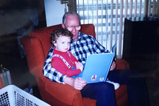 Grandfather shares a story with his grandchild while relaxing in a comfortable armchair.