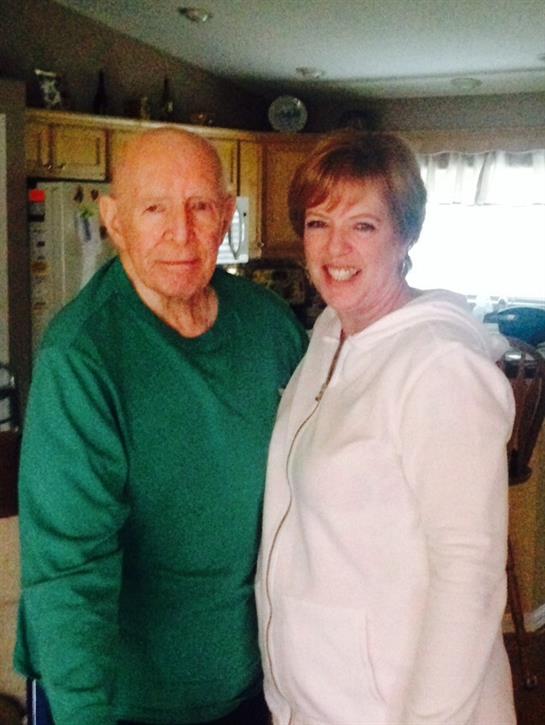 Elderly man and woman smile together in a warm kitchen, capturing a heartfelt moment of connection.