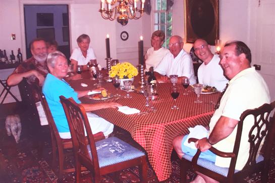 Friends enjoy a lively dinner together around a beautifully set table with delicious food.