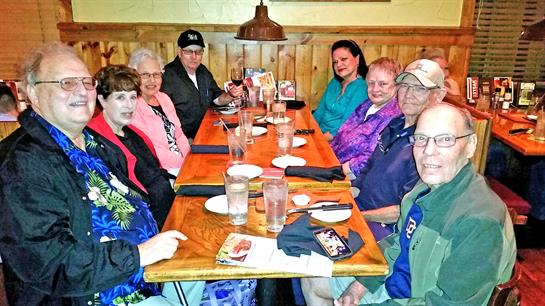 Family and friends enjoy dinner at a rustic wooden table, sharing stories and smiles together.