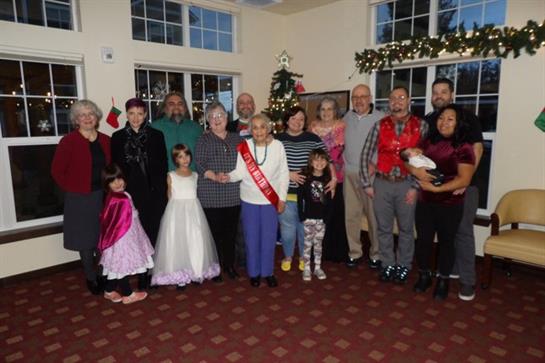 Group of people smiling and enjoying a festive holiday celebration in a decorated hall.