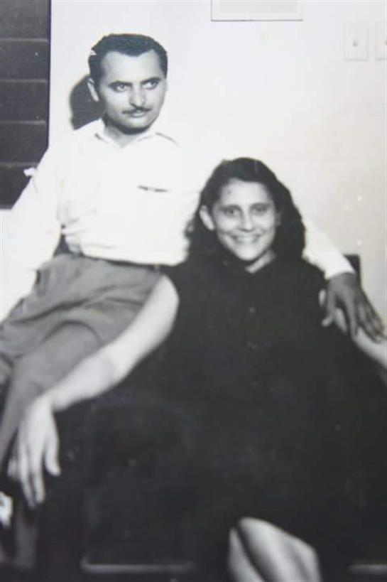 A couple smiles while sitting closely together in a warm, inviting indoor environment.