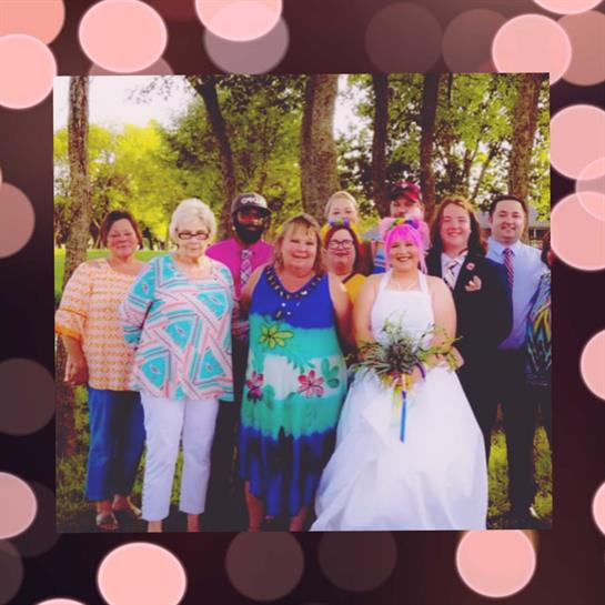 Friends and family pose together to celebrate a joyful wedding day amid trees and greenery.