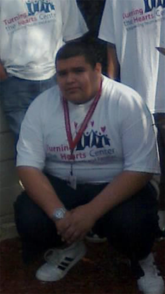 A volunteer sits with peers in a youth center, showing active support and participation.