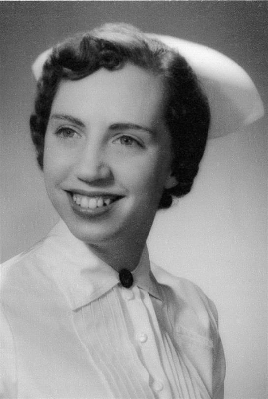 Nurse with a cheerful expression wears a classic uniform and cap, showcasing her profession.