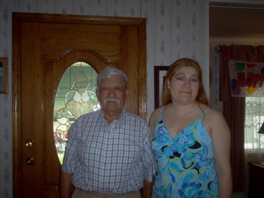 Grandfather and granddaughter smile together at home near a decorative door during sunlight.