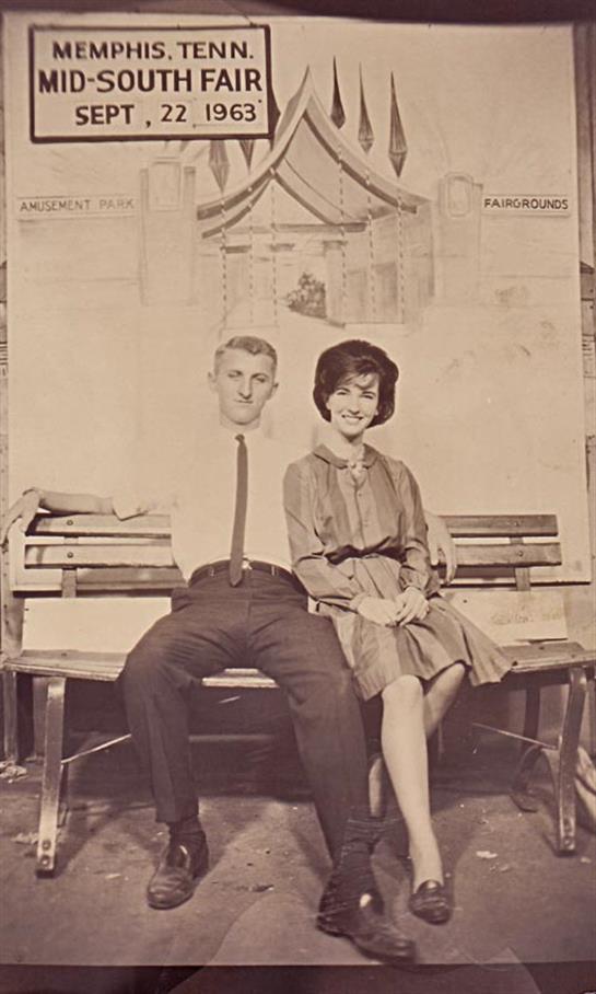 A couple enjoys a moment together seated on a bench in a park while surrounded by vintage scenery.