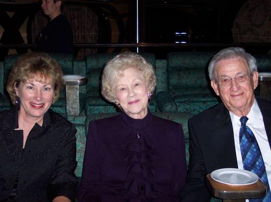 Three elderly friends sit on a comfortable couch, sharing stories and laughter at a gathering.