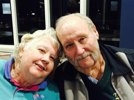 Elderly couple sharing a joyful moment indoors, smiling closely while enjoying each other's company.