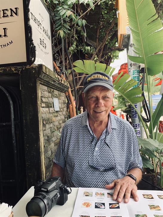 An elderly man is engaged in tasks at an outdoor cafe in Vietnam, showcasing local culture.