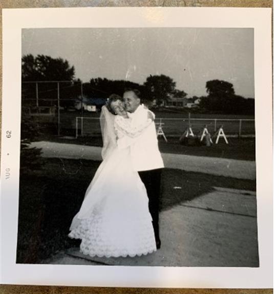 Newlyweds share a tender moment dancing outside during twilight, surrounded by nature.