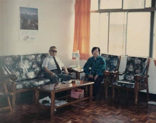 Two men are sitting together in a well-lit room, engaging in conversation on a sunny afternoon.