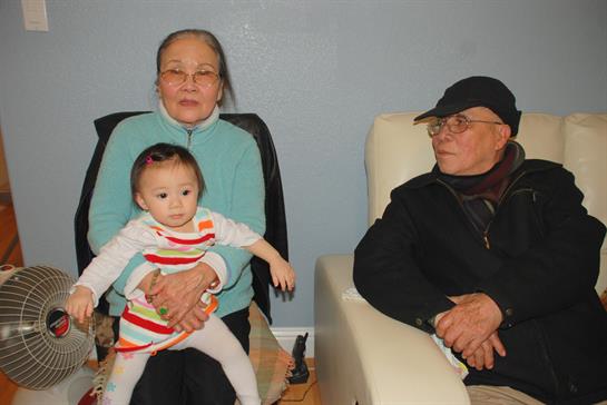 Three generations gather in a cozy living room, sharing smiles and warmth in a peaceful setting.