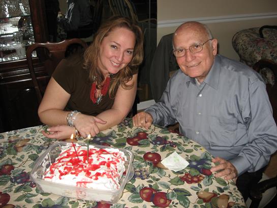 Family members share joyful moments while cutting a cake at a decorated table in a warm home.