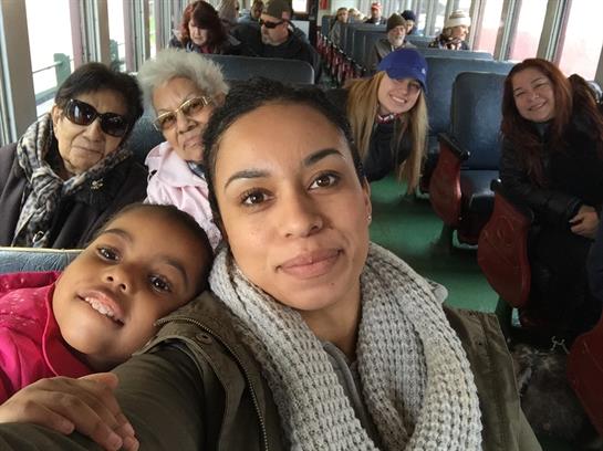 A woman and a child pose closely for a selfie while riding a ferry with friends and family.