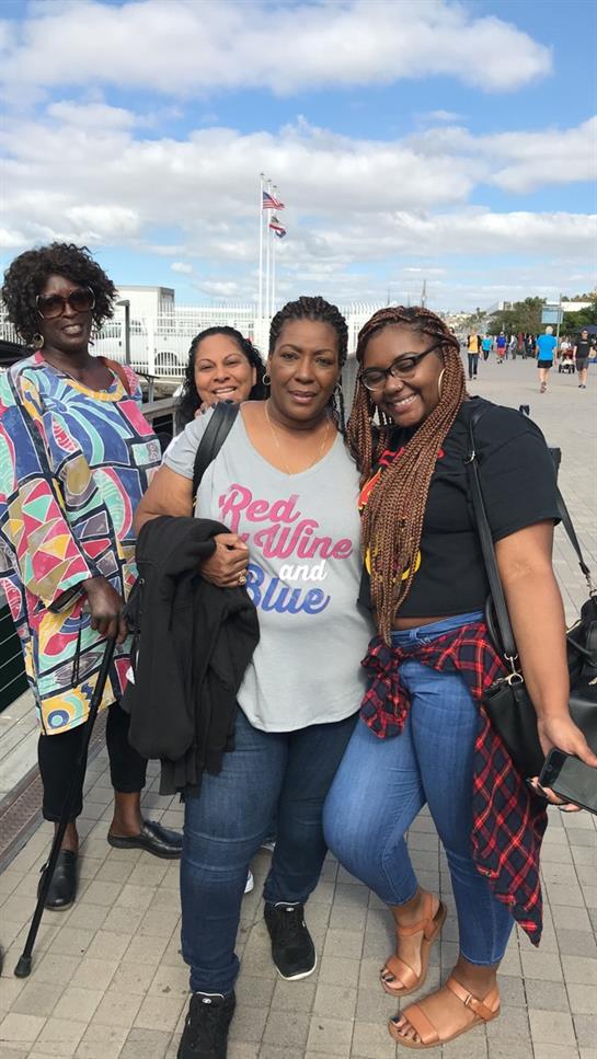 Four friends happily pose by the waterfront, celebrating their friendship and the sunny day.