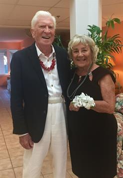 Two elegantly dressed seniors smile happily at a vibrant celebration.