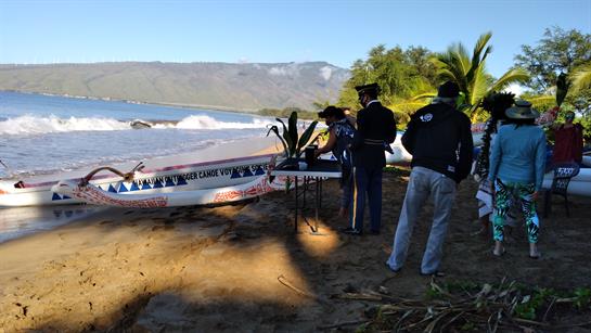 Fishermen getting ready to launch a boat on the sandy shore with clear skies and ocean waves.