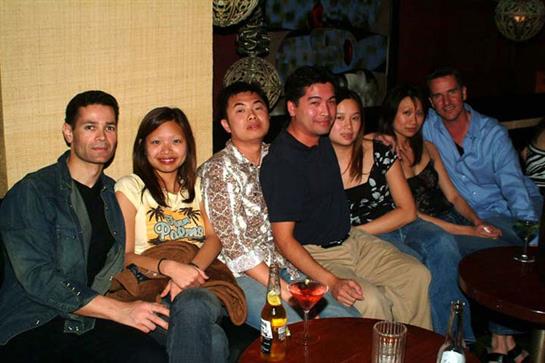 Friends gather together on a cozy couch in a vibrant bar while enjoying drinks and conversation.