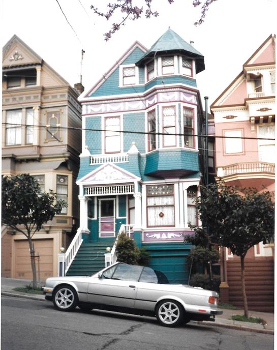 A vibrant Victorian house stands out with its ornate architecture and bright colors.