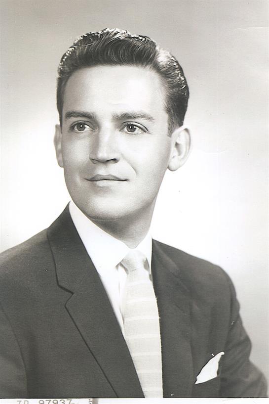 Portrait features a young man looking confidently at the camera, dressed in a suit and tie.