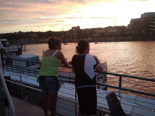 Two friends stand by the water, taking in the vibrant sunset and enjoying their time together.