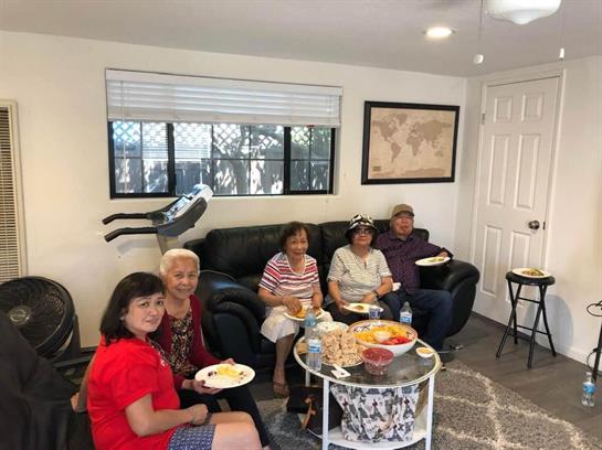 A group of friends shares laughter and snacks in a bright living room during a weekend gathering.