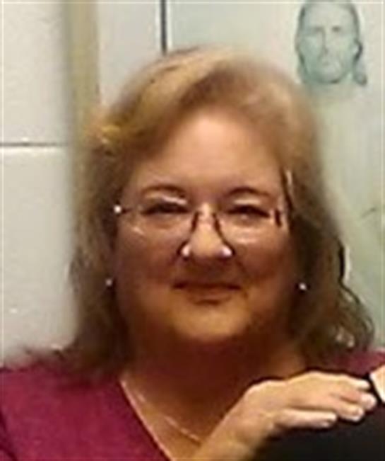 A cheerful woman sits comfortably, smiling warmly and enjoying the moment in a cozy atmosphere.