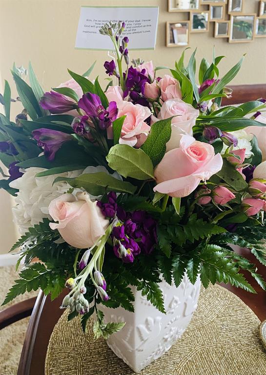Colorful arrangement of roses and lilies in a white vase, creating a lovely centerpiece indoors.