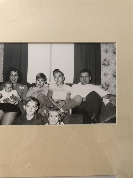 A lively family gathering in a cozy living room with children and adults sitting on a couch.