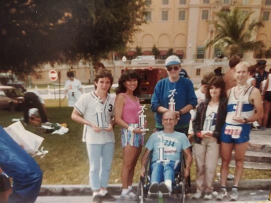 A group gathers in a park to celebrate their sports achievements, showcasing trophies and joy.