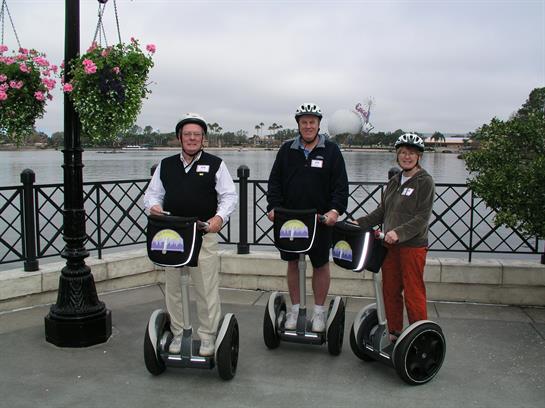Three tourists enjoy riding segways along the waterfront, dressed for outdoor exploration.