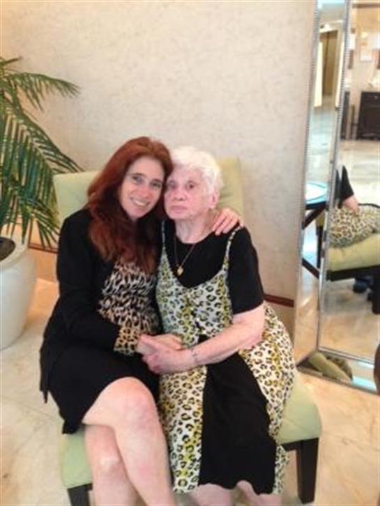 Two women share a warm embrace while sitting on a chair in a stylish indoor area.