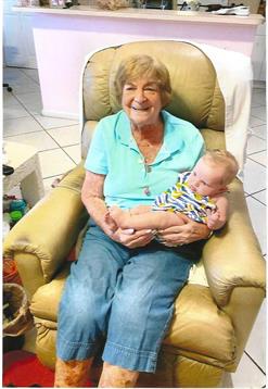 A joyful grandmother holds her baby grandchild in her lap, cherishing a warm moment together.