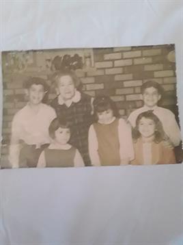 A gathering of children with an adult relative, all dressed in vintage clothing, sharing smiles.