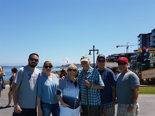 Group of six adults enjoying each other's company on a sunny beach day with vibrant ocean views.