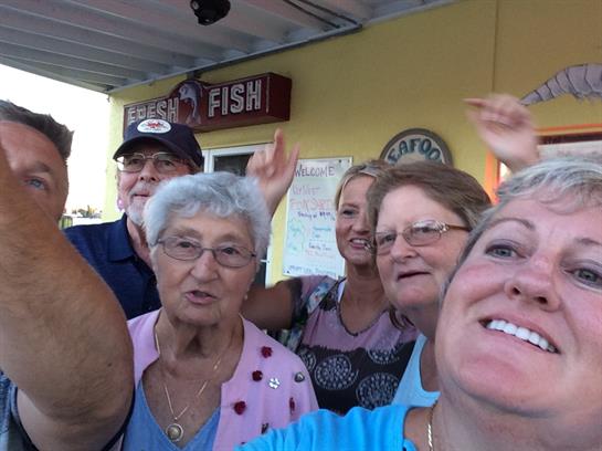 A cheerful group of friends gathers together at a waterfront eatery, enjoying their time.