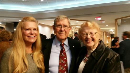 Three people smiling and enjoying each other's company at a festive indoor event.