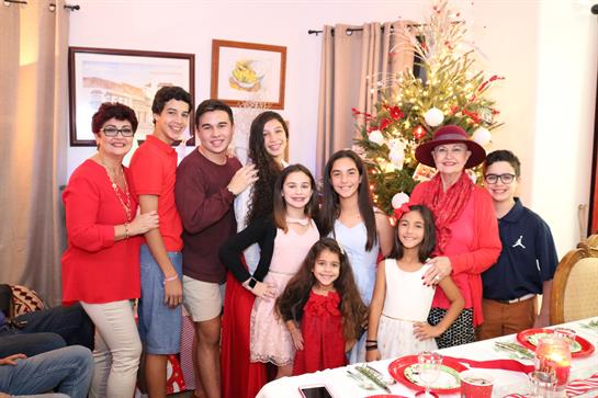 A big family joyfully celebrates a special occasion in festive attire at home.