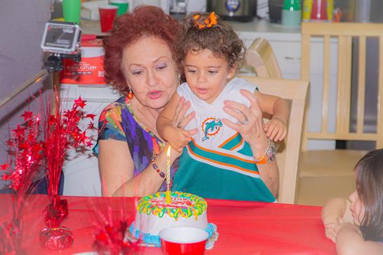 A grandmother and granddaughter share a joyful moment at a festive birthday celebration.