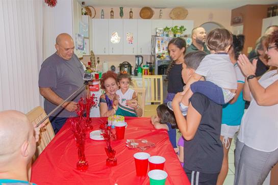 Family members enjoy a lively gathering with food, laughter, and games in a cozy home setting.